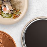 A tan one inch round custom button magnet with a rabbit wearing a scarf and fall foliage